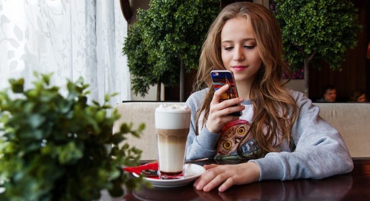 Mädchen mit Smartphone am Tisch