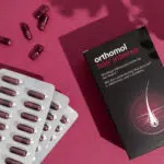 Orthomol-Kapseln auf einem roten Hintergrund